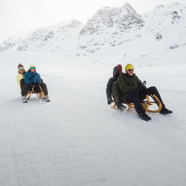Trois personnes assises sur une luge dans la neige