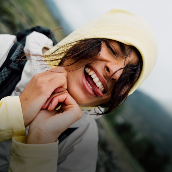 Une femme en tenue outdoor estivale en équilibre sur des pierres au bord d’un lac
