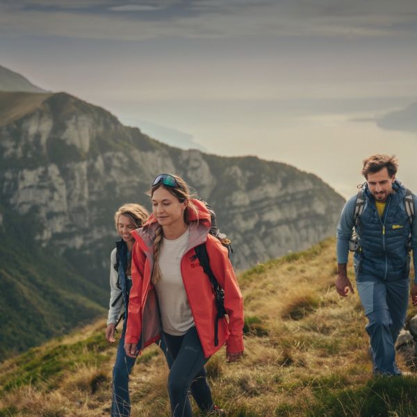 Drei Personen in frühlingshafter Wanderkleidung in bergiger Landschaft
