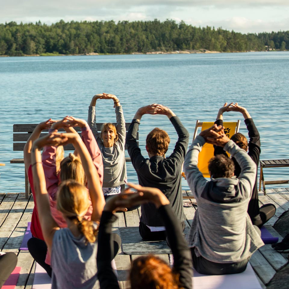 Mann in schwarzem Shirt steht vor einem Stand mit Outdoor-Bekleidung und Markenflaggen im Hintergrund
