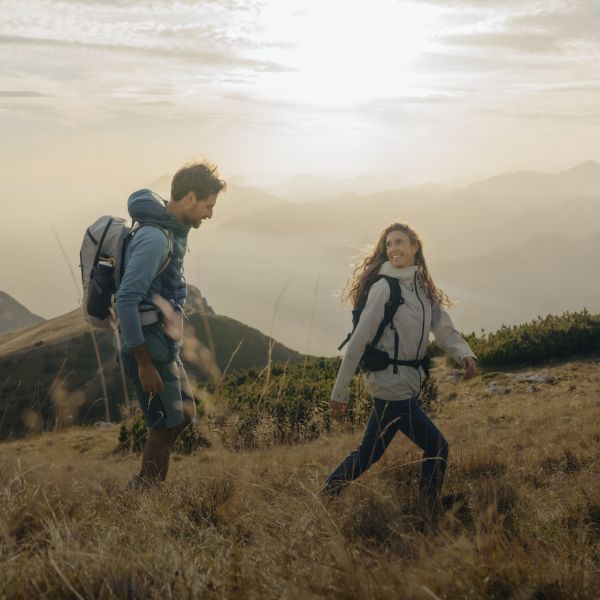Une femme et un homme en vêtements de randonnée en haut d’une montagne