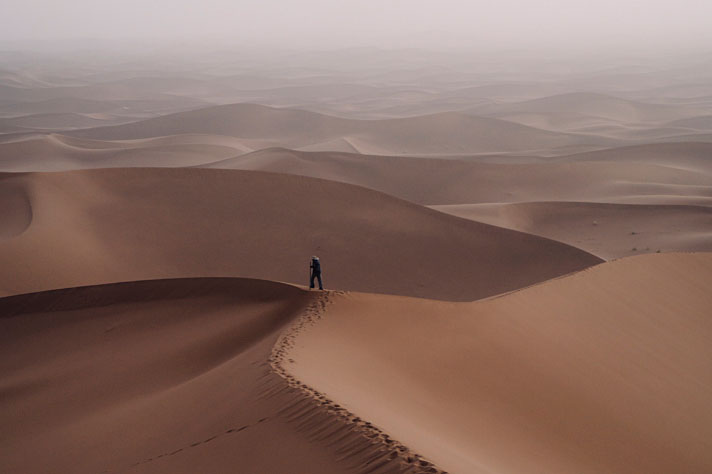 Un homme se tenant sur une dune dans le désert de sable