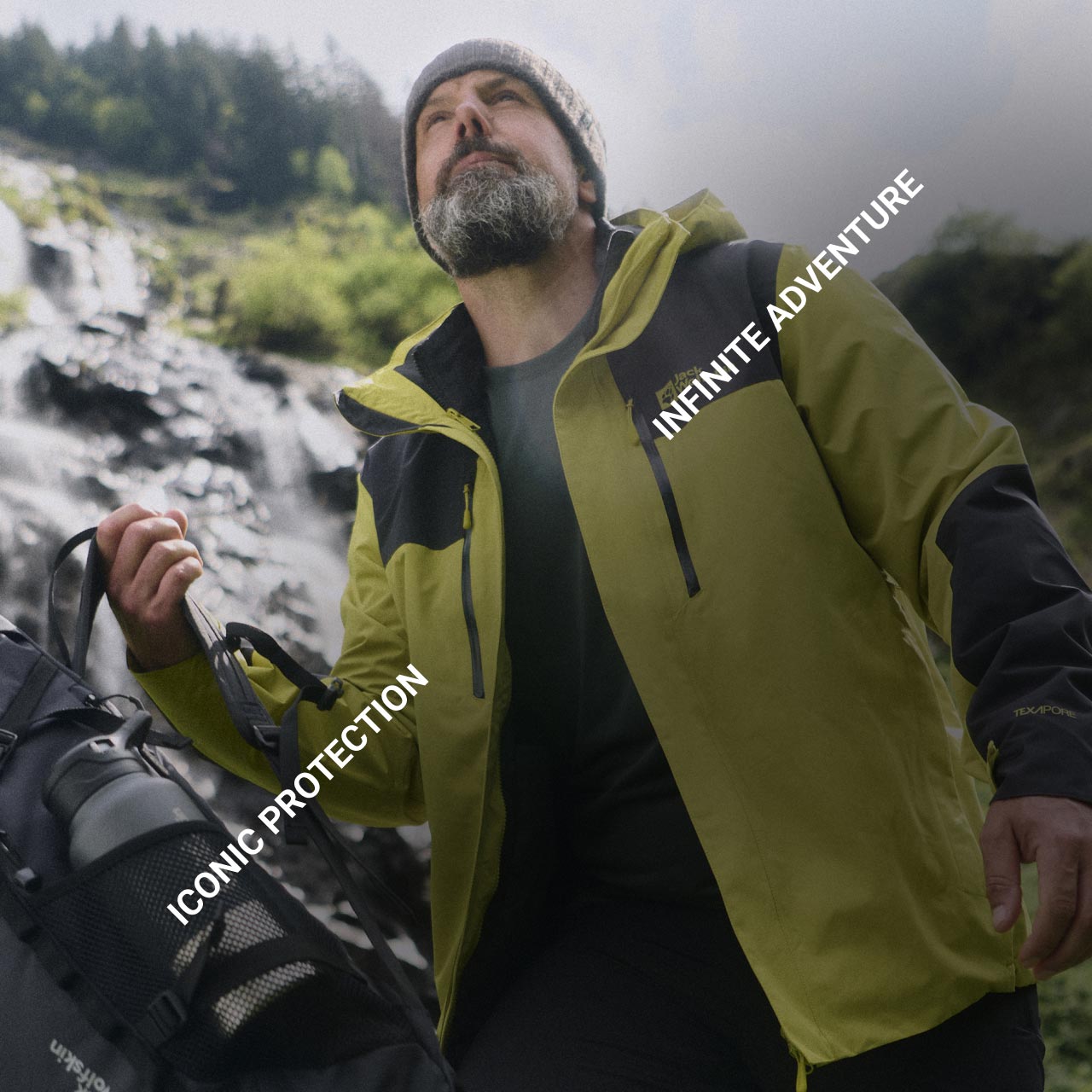 Un homme avec une veste jaune et un bonnet beige est debout dans la nature et regarde vers le haut. Le texte est le suivant : « Iconic Protection » et « Infinite Adventure »