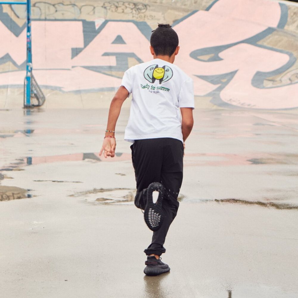 Junge läuft auf Asphalt mit Graffit im Hintergrund