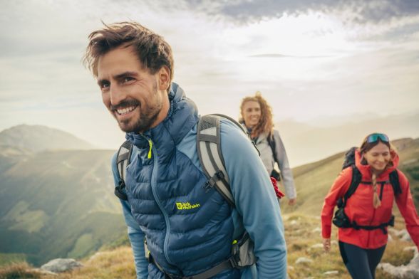 Mann und zwei Frauen in Wanderkleidung in bergiger Landschaft