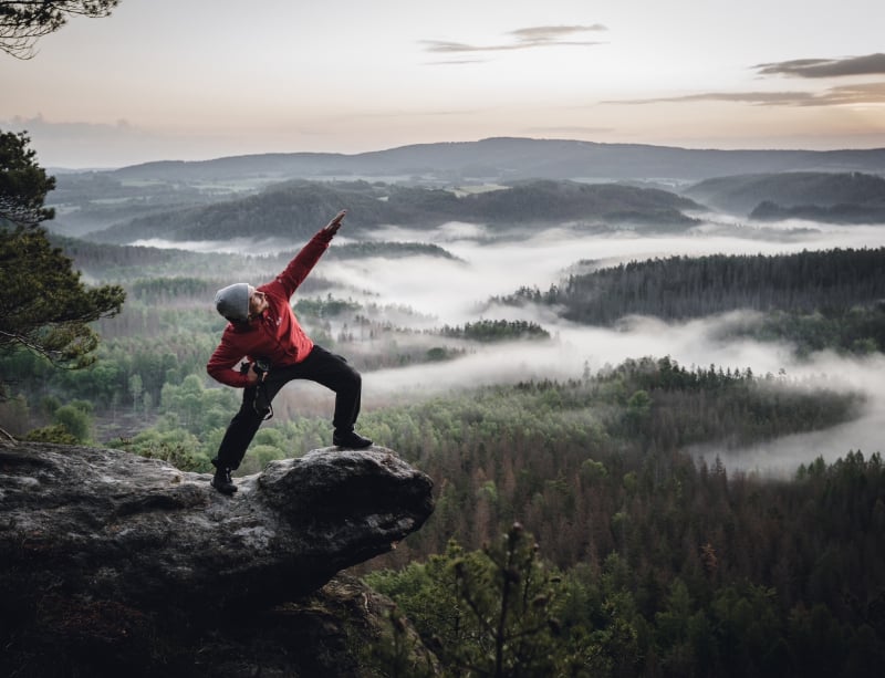 Tom auf einem Felsen über einem Nebelwald