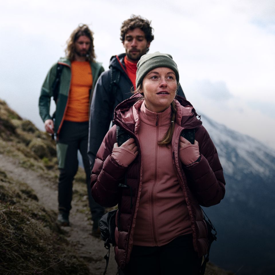 Trois randonneurs habillés chaudement marchent sur une montagne