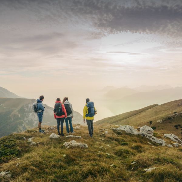 Quatre randonneurs vus de dos dans un paysage de montagne printanier